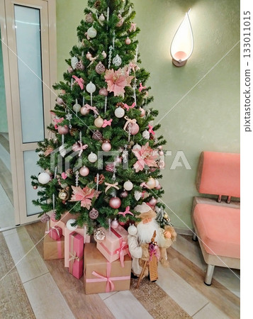 Christmas tree with pink ornaments and gifts in cozy interior 133011015