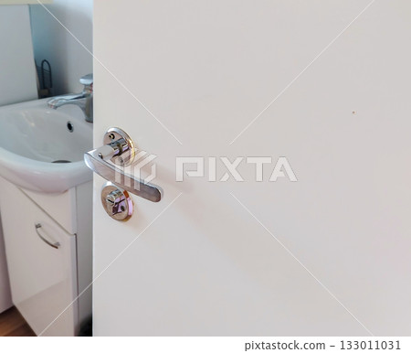 White door with chrome handle and lock view to bathroom sink 133011031