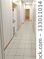 Bright office or clinic hallway with white doors and tiled floor 133011034