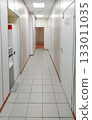 Bright office or clinic hallway with white doors and tiled floor 133011035