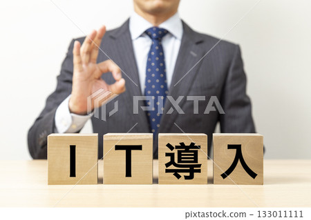 A businessman making an OK pose with a block that says "IT introduction" 133011111