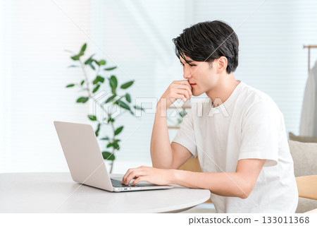 Young Asian man using laptop in the living room at home (investment, shock, trouble, decline, risk) Young Asian man using laptop in the living room at home (investment, shock, trouble, decline, risk) 133011368