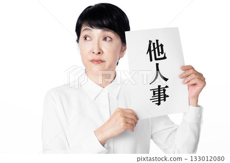 A senior woman with an exasperated expression holding a piece of paper that says "It's not my business" A senior woman with an exasperated expression holding a piece of paper that says "It's not my business" 133012080