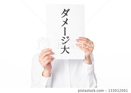 A person wearing a white shirt holding a piece of paper with the words "heavy damage" written on it in both hands A person wearing a white shirt holding a piece of paper with the words "heavy damage" written on it in both hands 133012081
