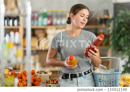 Woman choosing juice in supermarket Woman choosing juice in supermarket 133012199