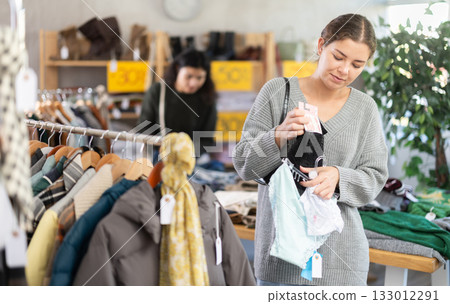 Girl is busy looking at clothes items in store, she chooses panties Girl is busy looking at clothes items in store, she chooses panties 133012291