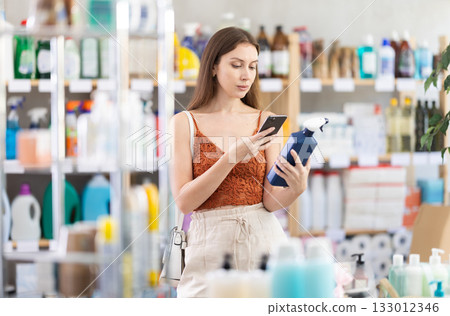 Young female customer scanning barcode on disinfectant spray in store 133012346