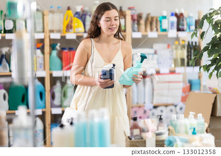 Young woman chooses cleaning spray in store Young woman chooses cleaning spray in store 133012358