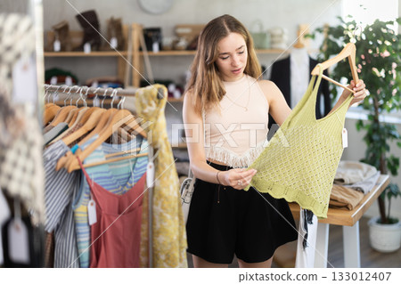 Selective young woman choosing something for summer in clothing store Selective young woman choosing something for summer in clothing store 133012407