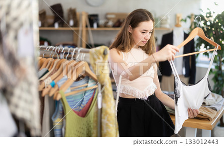 Selective young woman choosing something for summer in clothing store 133012443