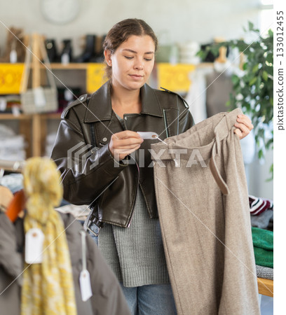 In sales area of store, woman customer chooses trousers 133012455