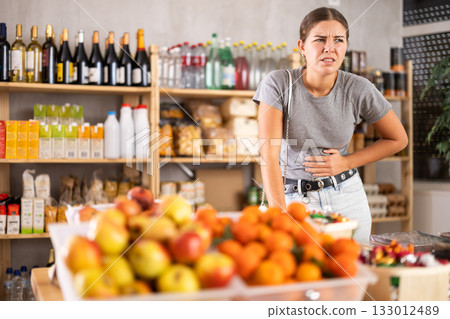 Woman in the store holding her stomach Woman in the store holding her stomach 133012489