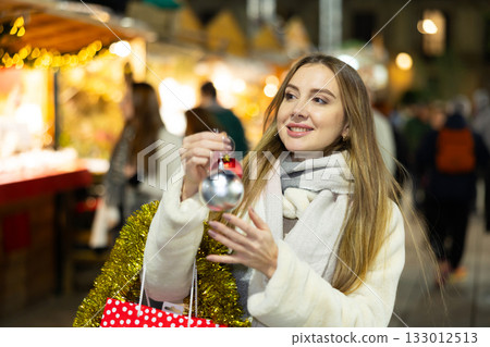Young woman has purchased decorations for Christmas tree, tinsel and colorful balls 133012513