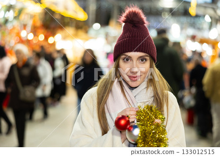 Young woman has purchased decorations for Christmas tree, tinsel and colorful balls Young woman has purchased decorations for Christmas tree, tinsel and colorful balls 133012515