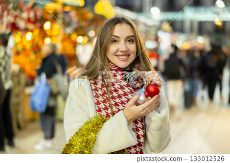 Young woman has purchased decorations for Christmas tree, tinsel and colorful balls 133012526