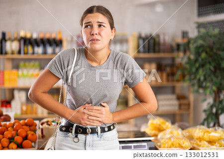 Woman in the store holding her stomach Woman in the store holding her stomach 133012531