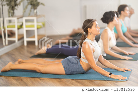 Young girl performing Cobra Pose during group yoga training Young girl performing Cobra Pose during group yoga training 133012556