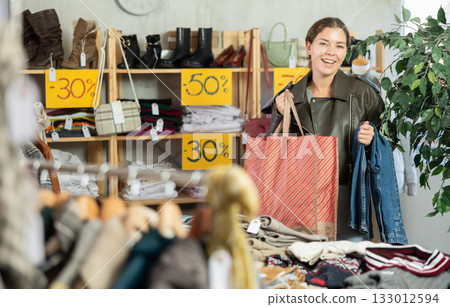 In sales area of store, woman customer chooses trousers In sales area of store, woman customer chooses trousers 133012594