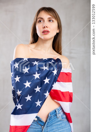 Scantily clad woman wrapped in USA flag posing in studio Scantily clad woman wrapped in USA flag posing in studio 133012599