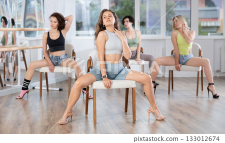Sitting on chair, girl with long hair train to perform lap dance, interacting with imaginary partner 133012674