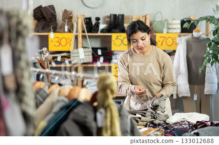 Portrait of latina woman selecting trousers in clothing shop. Sale of winter clothing collection Portrait of latina woman selecting trousers in clothing shop. Sale of winter clothing collection 133012688