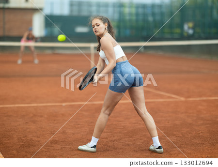 Young woman making serve while playing tennis Young woman making serve while playing tennis 133012694