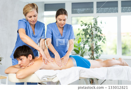 Professional masseuse teaching massage techniques to trainee 133012821