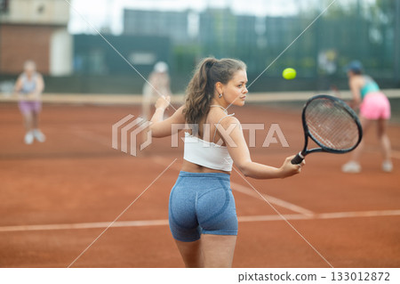 Two young women playing tennis against elderly women 133012872
