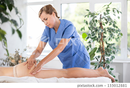 Professional masseuse performing anti-cellulite thigh and buttocks massage to woman Professional masseuse performing anti-cellulite thigh and buttocks massage to woman 133012881