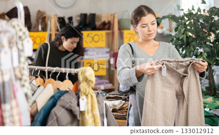 In sales area of store, woman customer chooses trousers 133012912