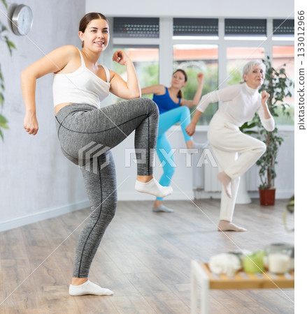 Young girl practicing energetic dance with group of women 133012966
