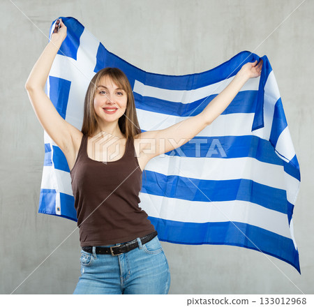 Happy woman posing with flag of Greece on gray background 133012968