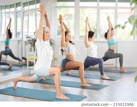 Elderly woman doing pilates in group in studio Elderly woman doing pilates in group in studio 133012986