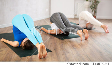 Young female yoga instructor showing others plough pose in wellness center 133013051