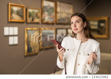 Woman in a Jacket and with a Phone in a Museum of Paintings 133013062