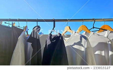 Clothes hanging neatly on hangers under the sun, gently swaying in the breeze—offering a perfect glimpse of fresh laundry days, clean fabric, and simple everyday beauty in every scene. Clothes hanging neatly on hangers under the sun, gently swaying in the breeze—offering a perfect glimpse of fresh laundry days, clean fabric, and simple everyday beauty in every scene. 133013127