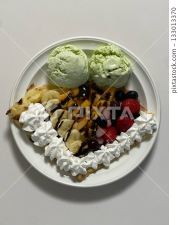 Delicious ice cream-filled crepes, drizzled with chocolate sauce and topped with fresh fruits. Perfect for dessert photography, showcasing the delightful combination of flavors and texture 133013370