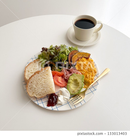 A delightful brunch spread featuring a mix of savory and sweet dishes, including fresh pastries, eggs, seasonal fruits, and a hot beverage. A perfect mid-morning indulgence. 133013403