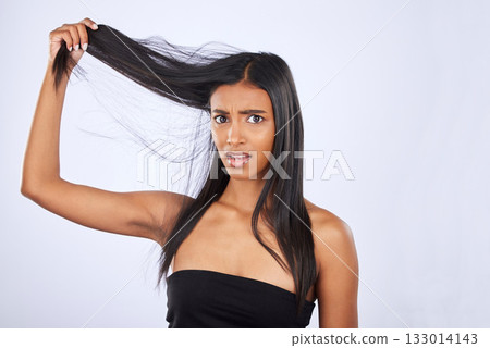 Hair damage, breakage and portrait of a frustrated woman isolated on a white background in studio. Bad, unhappy and an Indian girl sad about split ends, tangled hairstyle and frizzy haircare 133014143