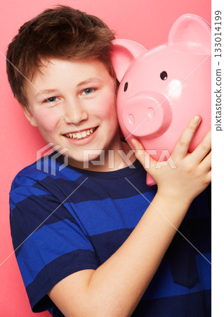 Happy boy, portrait and piggy bank with smile for savings, money or coins against a pink studio background. Little child or kid holding piggybank and smiling for financial freedom, cash or investment 133014199
