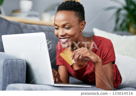 Laptop, credit card and black woman relax on a sofa for online shopping, e commerce and membership. Banking, credit score and female African person happy with payment, booking or customer experience 133014514
