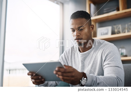 Internet, tablet and man on couch reading social media post, email or streaming video on subscription service. Scroll, search and person with serious face and checking online movie website on sofa. Internet, tablet and man on couch reading social media post, email or streaming video on subscription service. Scroll, search and person with serious face and checking online movie website on sofa. 133014545