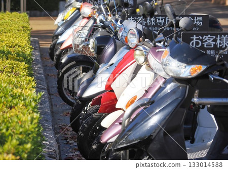Many scooters parked in the parking lot reserved for customers of a commercial facility 133014588