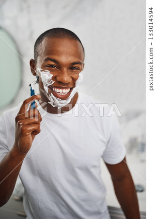 Black man, smile and shaving with blade, soap or grooming in mirror for self care in home bathroom. African guy, foam or cream for facial hair removal, razor or clean for hygiene in morning at house 133014594