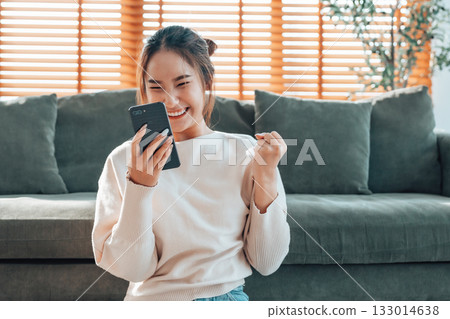 Happy young asian woman relax on comfortable couch at home texting messaging on smartphone Happy young asian woman relax on comfortable couch at home texting messaging on smartphone 133014638