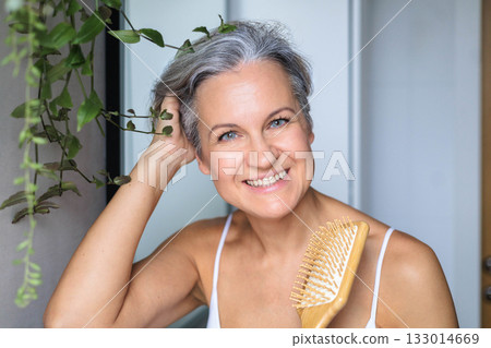 Portrait of a beautiful, smiling gray-haired European woman with a wooden comb. Concept anti-age. 133014669