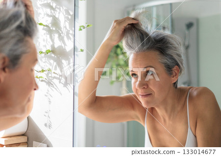 European beautiful and smiling middle-aged woman combing her gray hair 133014677