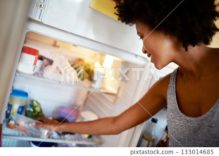 Woman, search fridge and food with smile, hungry and thinking for diet, meal and choice in home kitchen. Young african girl, happy and decision for breakfast, lunch or dinner in house for nutrition 133014685