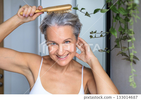 Portrait of a beautiful, smiling gray-haired European woman with a wooden comb. Concept anti-age. 133014687