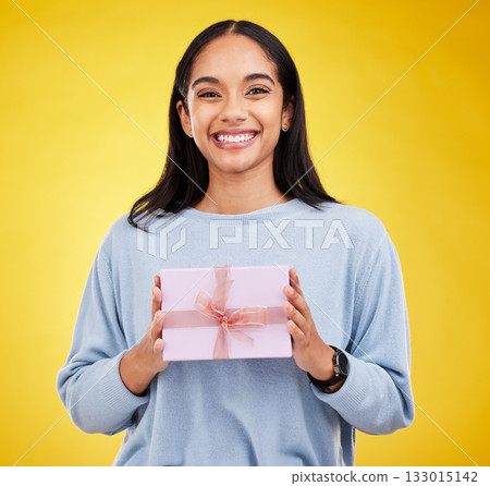 Happy woman, portrait and gift box in a studio with a smile from surprise present for birthday. Giveaway prize, isolated and yellow background of a young female student feeling positive and cheerful Happy woman, portrait and gift box in a studio with a smile from surprise present for birthday. Giveaway prize, isolated and yellow background of a young female student feeling positive and cheerful 133015142